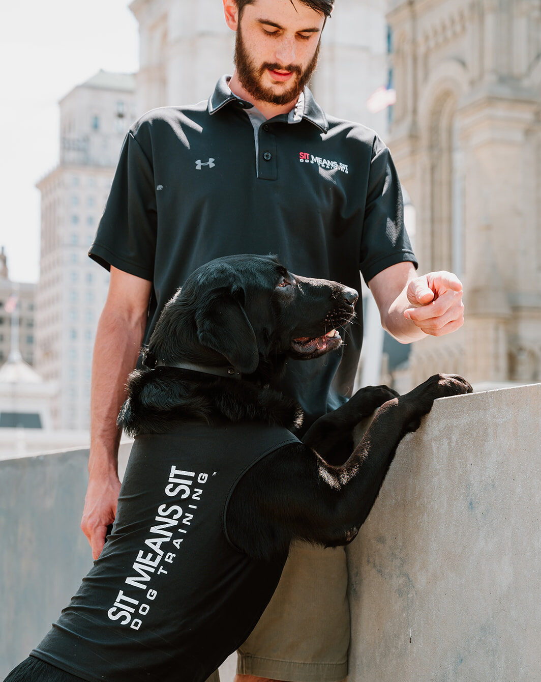 Dog trainer gesturing to a black dog standing on two feet